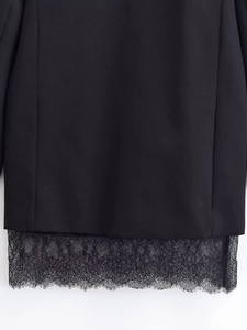 Detailed macro view of the black fabric and intricate floral lace hem on this dress