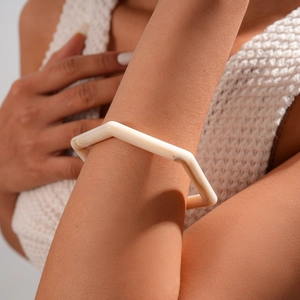 Close-up of minimalist ivory resin geometric bracelet on model with white knitwear