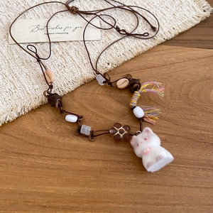 Detail of a handmade cat pendant necklace with brown woven cord and assorted beads
