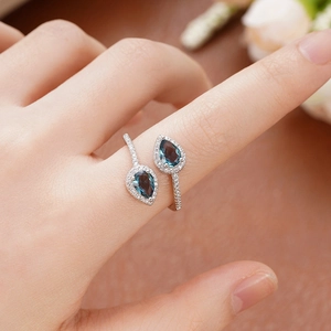Detailed view of dual pear-cut blue stone rings with halo setting and pavé band