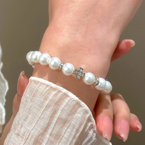 Detailed view of pearl bracelet featuring a silver cross pendant with sparkling zircons
