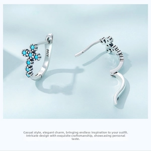 Close-up of S925 sterling silver hoop earrings with blue stone pave cross pendant