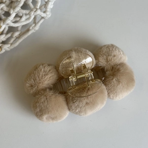 Detail of light brown plush ball hair claw clip with a transparent spring base