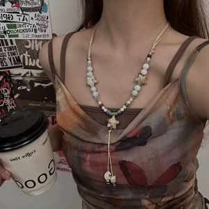 Detail of beaded necklace with star pendants worn by model in a bohemian setting
