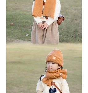 Detailed knit texture of autumn winter kids hat and scarf set with white heart embroidery