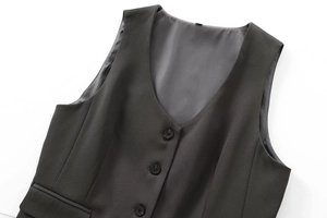 Détail macro du gilet noir à col en V avec texture du tissu et fermeture à trois boutons