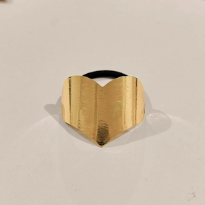 Close-up of golden heart metal hair tie with brushed texture and black elastic band