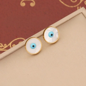 Detail shot of golden evil eye stud earrings with blue enamel on a jewelry box