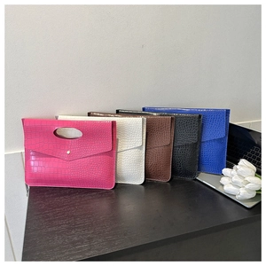 Detailed view of five crocodile pattern laptop sleeves in vibrant colors on a wooden table