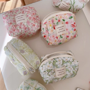Flat lay of multiple floral cotton cosmetic bags with zippers on a white surface