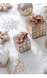 Golden plaid gift box ornaments with sequins and bows on white fur background