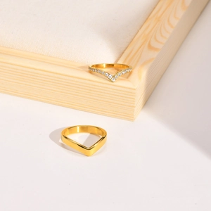 Detail view of two gold V-shaped chevron rings, one featuring sparkling cubic zirconia