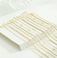 Detailed assortment of various gold-plated necklace chain styles on a white surface