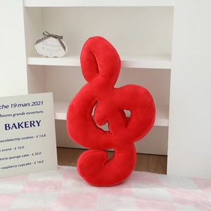 Vue macro du coussin en peluche rouge en forme de clé de sol avec tissu doux velours