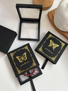 Detalle de caja de joyería de película PE negra con elegante estampado dorado de mariposa
