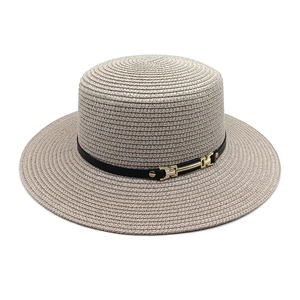 Détail du chapeau de paille gris avec ruban en cuir noir et boucle en métal doré