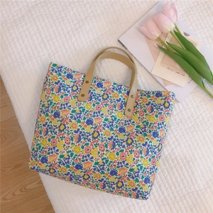 Flat lay of floral canvas tote bag with brown PU handles and decorative tulips