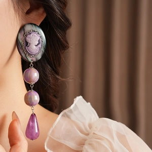 Detail of vintage cameo drop earrings with purple beads on a female model