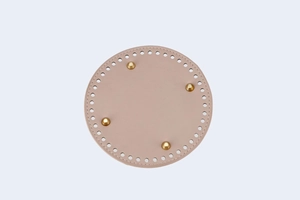 Macro view of 15cm round nude pink PU leather bag base with golden feet and pre-punched holes