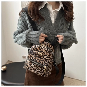 Close-up of leopard print mini backpack with golden zipper and leather texture details