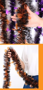 Close-up of black Halloween tinsel garland with orange pumpkin cutouts held by a model