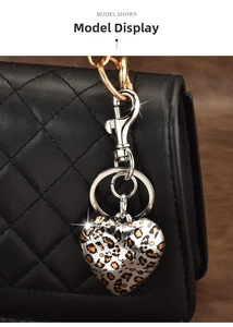 Close-up of leopard print heart keychain on a black quilted leather handbag with silver hardware