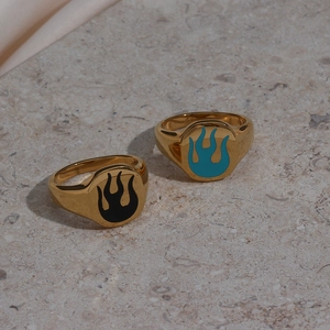 Close-up of gold stainless steel rings with black and turquoise enamel flame patterns