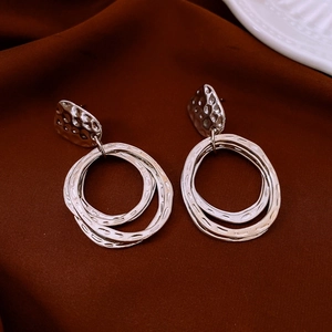 Detail of silver round pendant earrings featuring three-layer rings with hammered texture