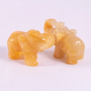 Detail view of two orange crystal elephant statues carved from translucent gemstone
