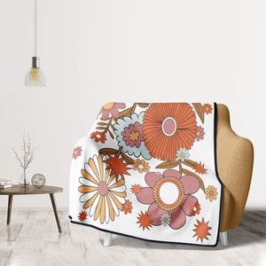Retro floral flannel throw blanket in orange and pink draped over an armchair