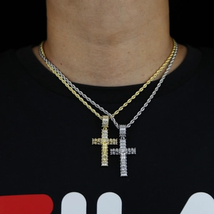 Dettaglio dei ciondoli a croce in oro e argento con zirconi su catene a corda