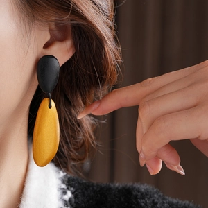 Close-up of minimalist black and yellow teardrop earrings on a female model