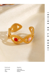 Detail of adjustable gold evil eye ring with colorful enamel inlay on silky fabric