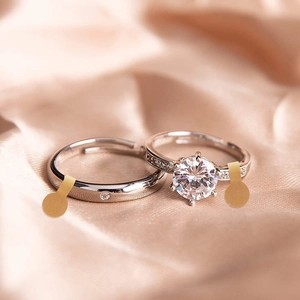 Macro shot of silver wedding rings with round zircon and pavé setting on silk