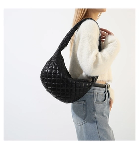 Close-up of black quilted puff shoulder bag with diamond stitching on a model
