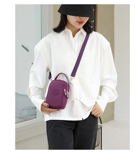Detail of purple nylon crossbody bag with three zippered compartments and adjustable strap