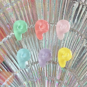 Macro shot of 6 colorful resin P-shaped alphabet charms with a glossy polished finish