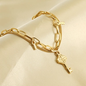 Detail of gold double-layer chain bracelet with floral key charms on silk background