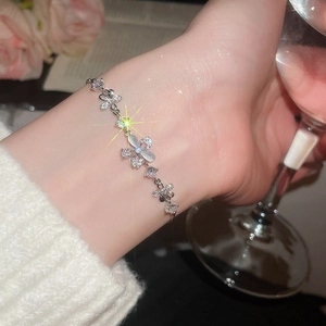 Detail of zircon and opal flower bracelet worn while holding a crystal glass