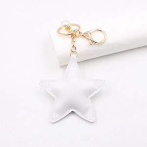 Detail of white star leather keychain with gold lobster clasp and mini pearl charm