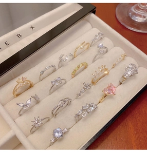 Detailed view of delicate gold and silver rings with colorful zircon heart and crown charms