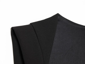 Macro shot of high-quality black twill fabric and jewel button detail on a chic romper