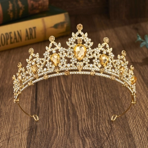 Baroque golden bridal crown with colorful rhinestones on a vintage wooden desk background