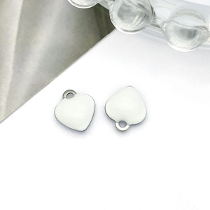Detailed close-up of white heart enamel charms with silver metal loops for DIY jewelry