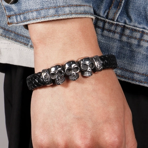 Men's black braided leather bracelet with five silver skull charms and magnetic clasp