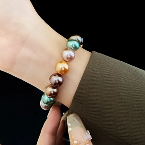 Vue détaillée des grandes perles multicolores dorées, roses et vertes sur le poignet