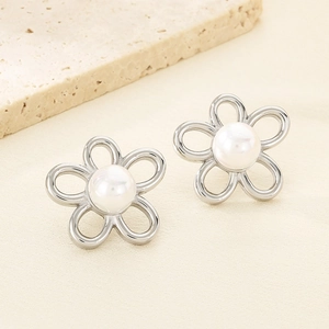 Vue macro de boucles d'oreilles fleurs argentées avec perle centrale et pétales évidés