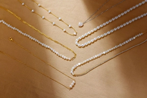 Detailed collection of S925 silver pearl necklaces with gold chains on textured fabric