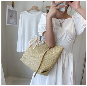 Detail of straw tote bag with brown leather strap and floral lace decoration