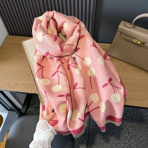 Pink cashmere-feel scarf with cherry pattern and tassels on a wooden surface